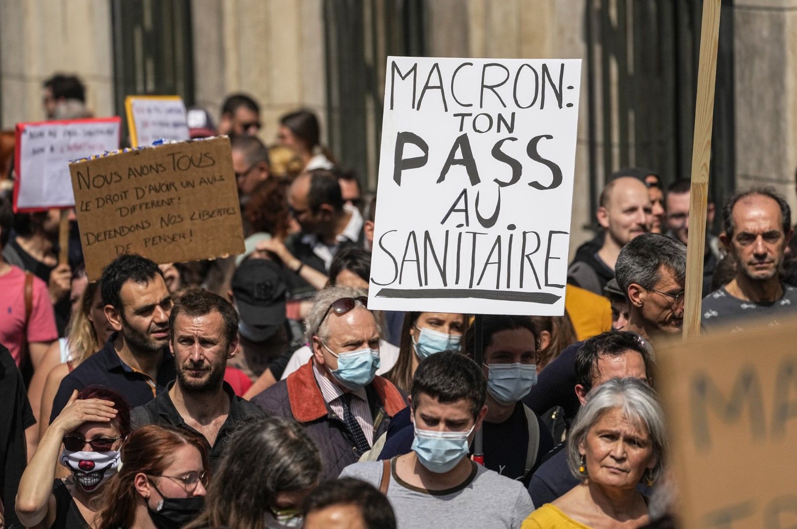 Протестиращи срещу ваксините държат плакат, на който пише: "Макрон, вашият здравен пропуск в тоалетната"