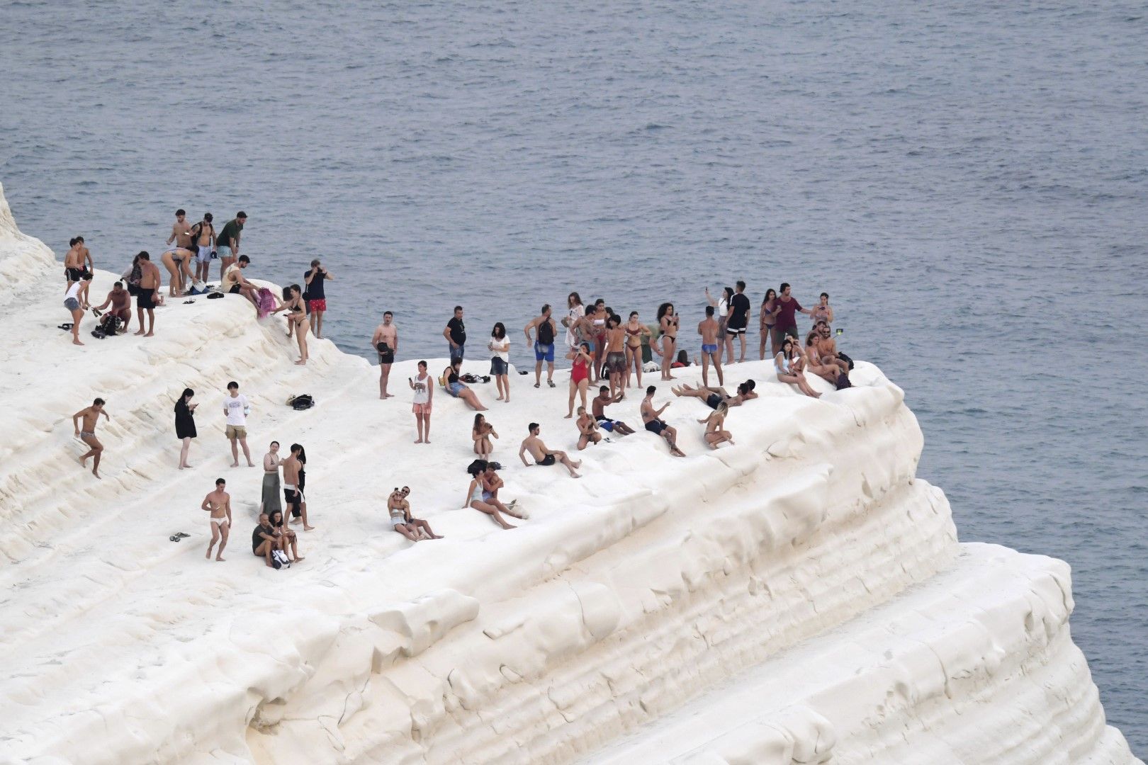 Хората търсят прохлада от морския бриз на скала в Южна Сицилия на 11 август