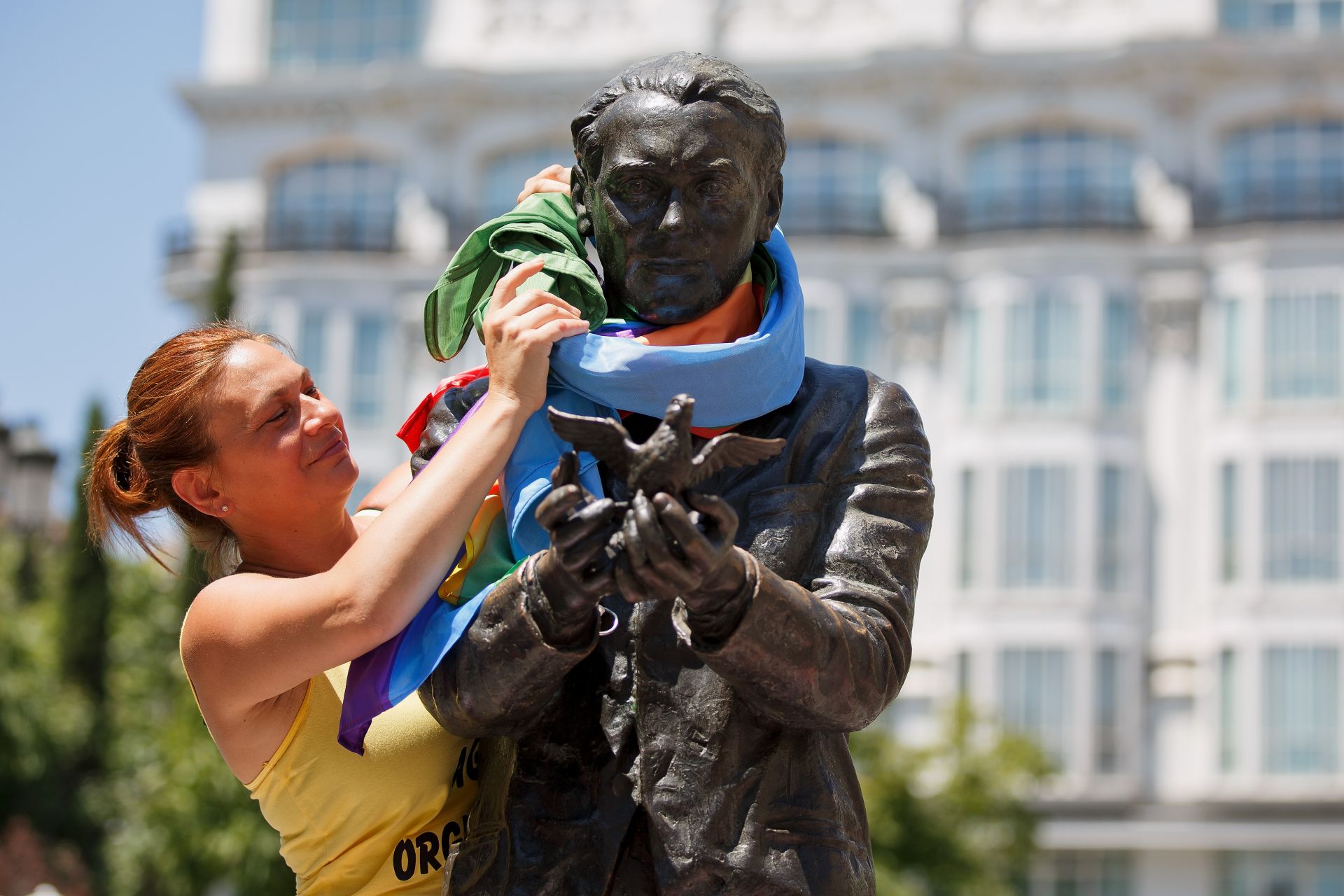 Дама връзва шалче на паметника на Лорка на площат "Санта Ана" по време на честването на рождението му