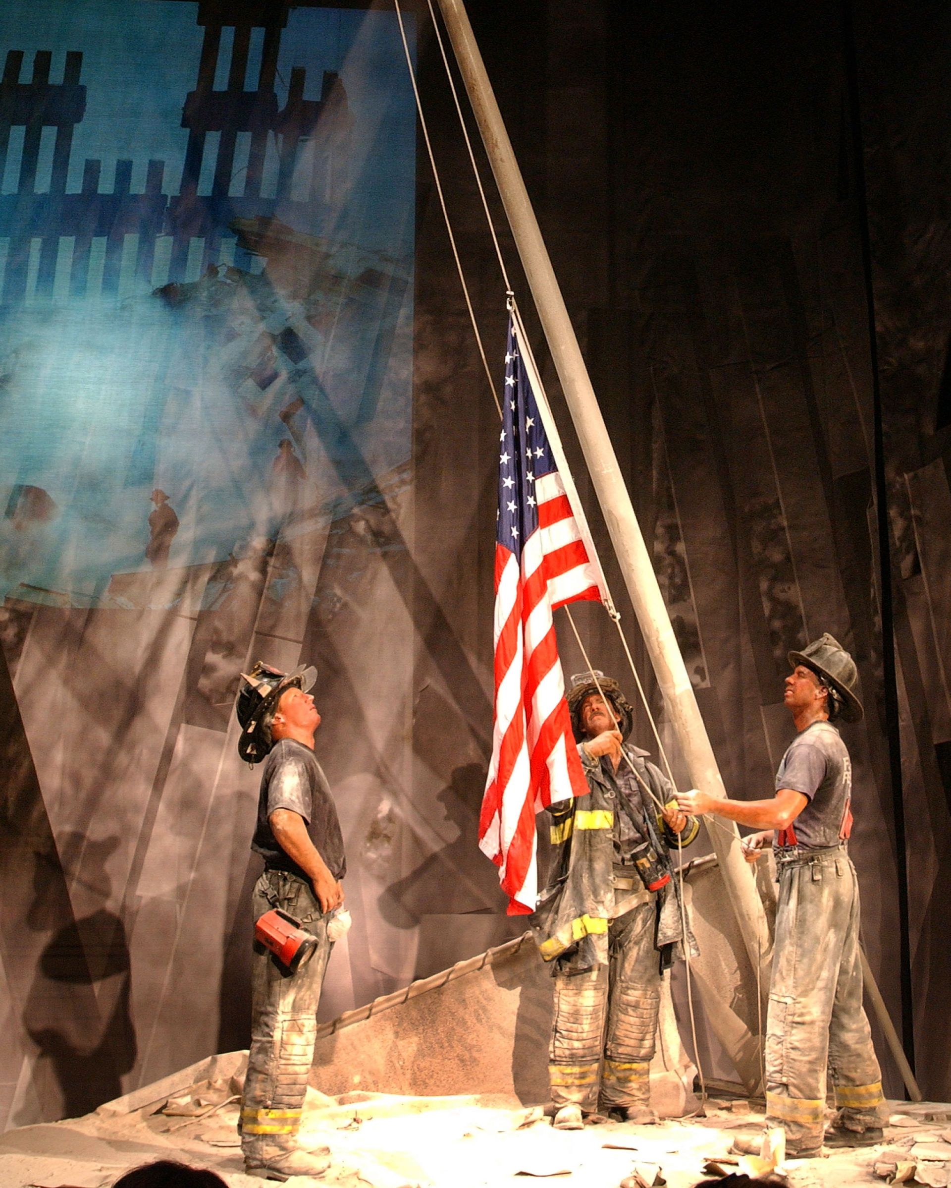Пожарникари вдигат американското знаме, попаднало под руините