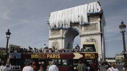 Туристи наблюдават последния етап от опаковането на Триумфалната арка в Париж (снимки)