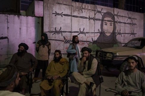 Талибани са седнали пред изрисувана стена с изобразена жена зад ограда от бодлива тел в Кабул