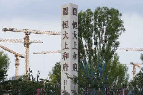 Строителни кранове на обект в бизост до рекламно пано на компанията за недвижими имоти Евъргранд в Пекин