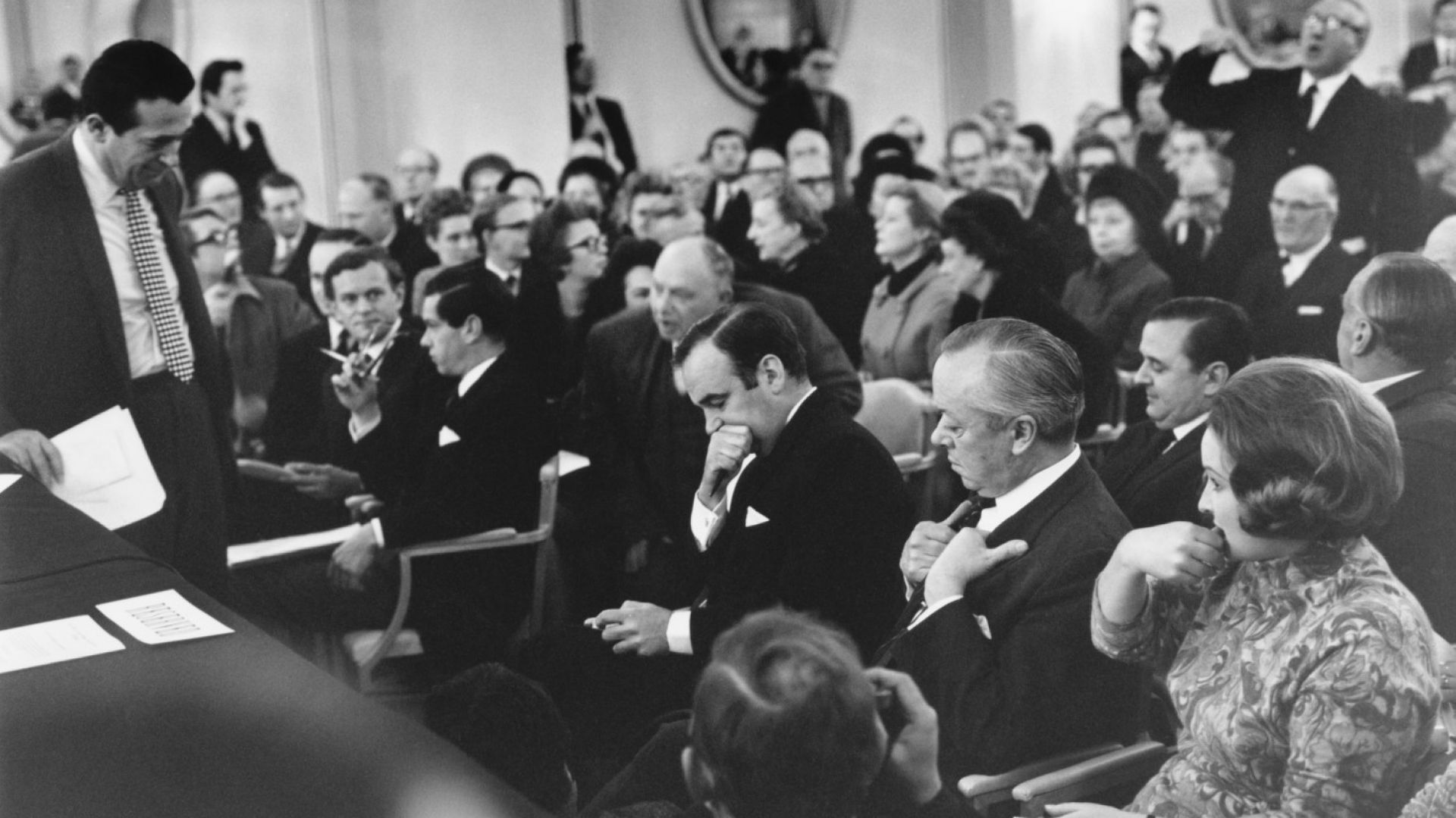 Съперниците Робърт Максуел, (изправен вляво) и Рупърт Мърдок (в средата) очакват гласуване на офертите им за вестник News Of The World по време на събрание на акционерите в Лондон, 2 януари 1969 г.