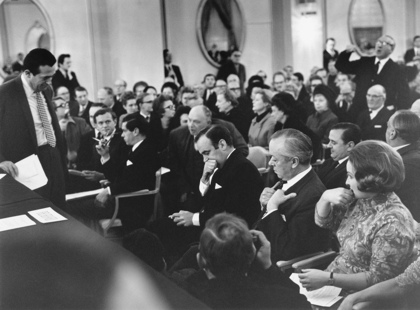 Съперниците Робърт Максуел, (изправен вляво) и Рупърт Мърдок (в средата) очакват гласуване на офертите им за вестник News Of The World по време на събрание на акционерите в Лондон, 2 януари 1969 г.