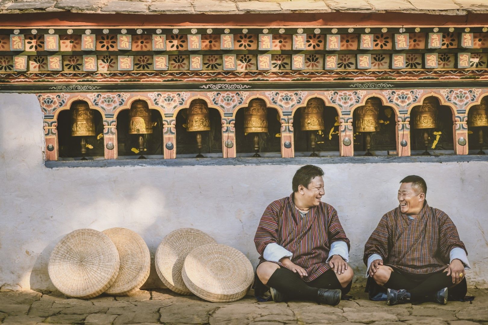 Бутанци стоят край молитвените колела в манастира в Паро Тактсанг