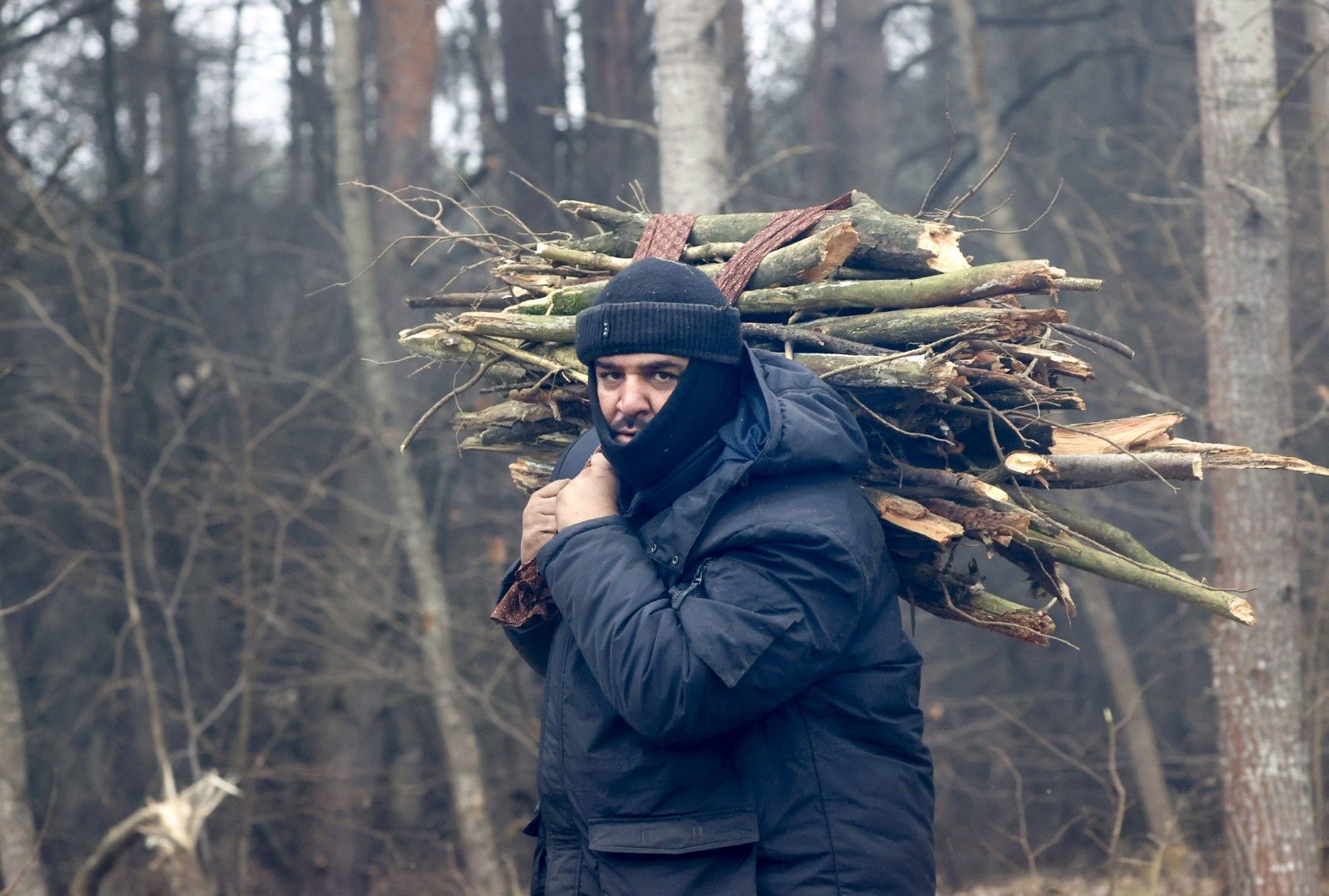 Мигрант от Близкия изток носи дърва за огрев в един от лагерите по границата между Беларус и Полша