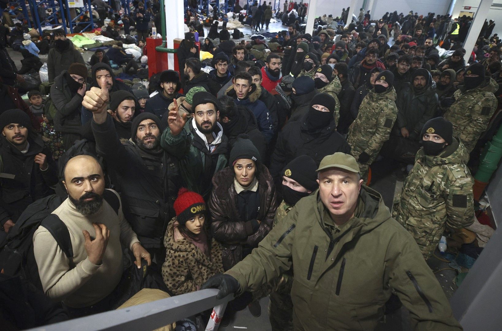 Помощникът на президента, инспектор Юрий Караев, вдясно, наблюдава как мигрантите се настаняват за нощувка в логистичния център на ГКПП "Кузница" на границата между Беларус и Полша близо до Гродно, Беларус, 18 ноември
