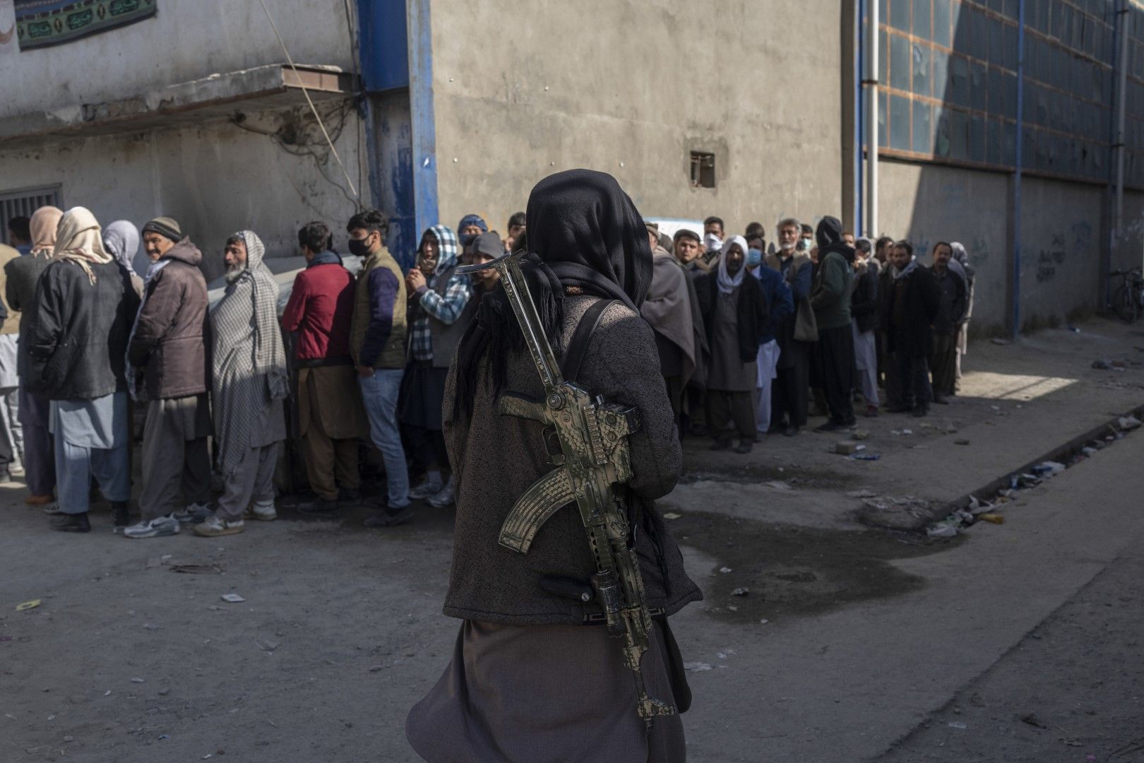Ноември, 2021 г. - Талибан наблюдава опашка за пари в офис, организиран от Световната организация по прехраната в Кабул, Афганистан Талибан наблюдава опашка за пари в офис, организиран от Световната организация по прехраната в Кабул, Афганистан
