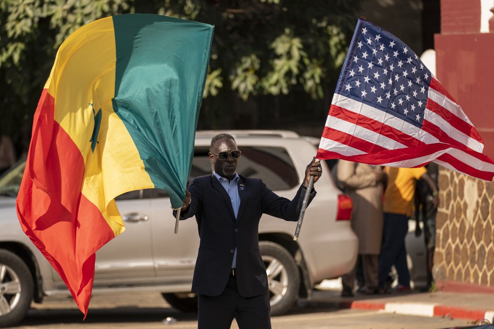 Мъж държи сенегалското и американското знаме по време на посещението на държавния секретар Антъни Блинкън в Дакар