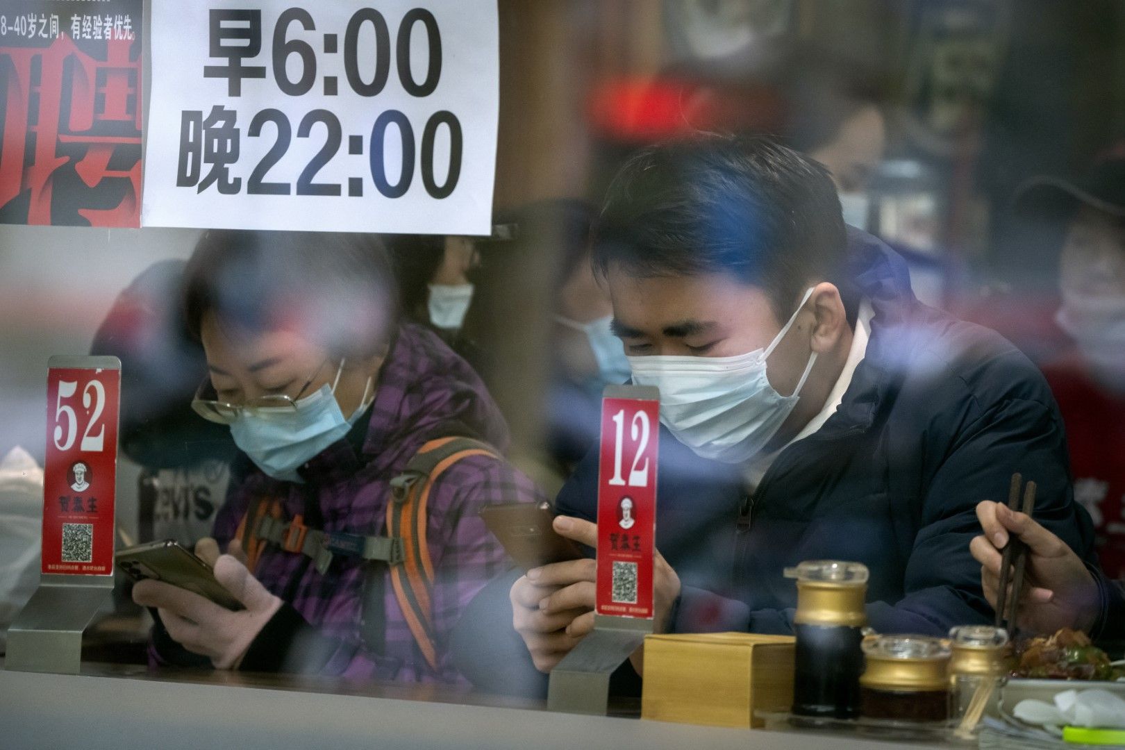 Китайци с маски чакат да се изпълнят поръчките им в уличен ресторант на открито в Пекин