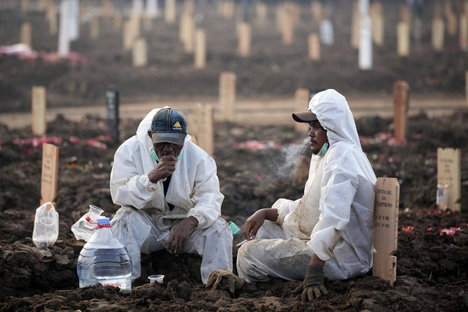 Работниците си почиват по време на натоварен ден на гробището Роротан, което е запазено за починалите от COVID-19, в Джакарта, Индонезия