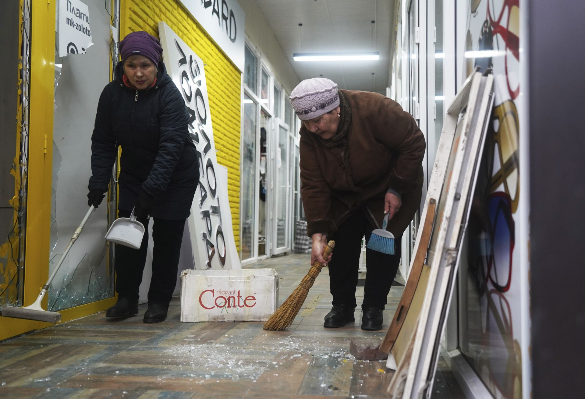 Собственици почистват магазина си, който беше разбит и ограбен по време на сблъсъци в Алмати