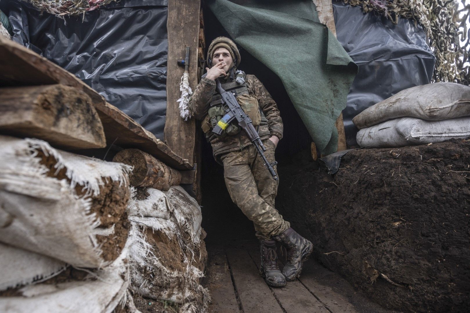 Украински войник пуши в окоп на фронтовата линия със сепаратистите в Донецка област, Украйна, понеделник, 10 януари 2022 г., Русия