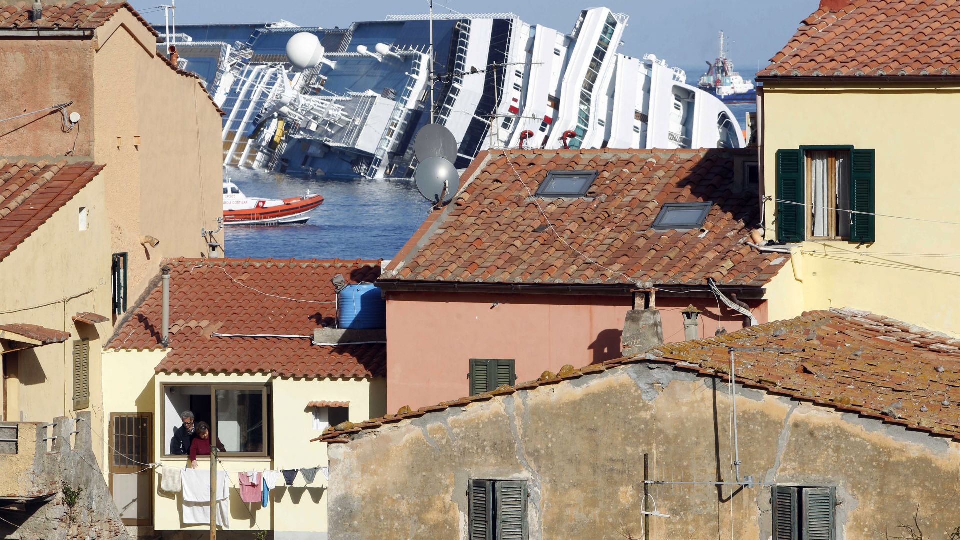 Претърпелият корабокрушение круизен кораб Коста Конкордия, Costa Concordia, се вижда на заден план, край тосканския остров Изола дел Джилио, Италия, събота, 21 януари 2012 г.
