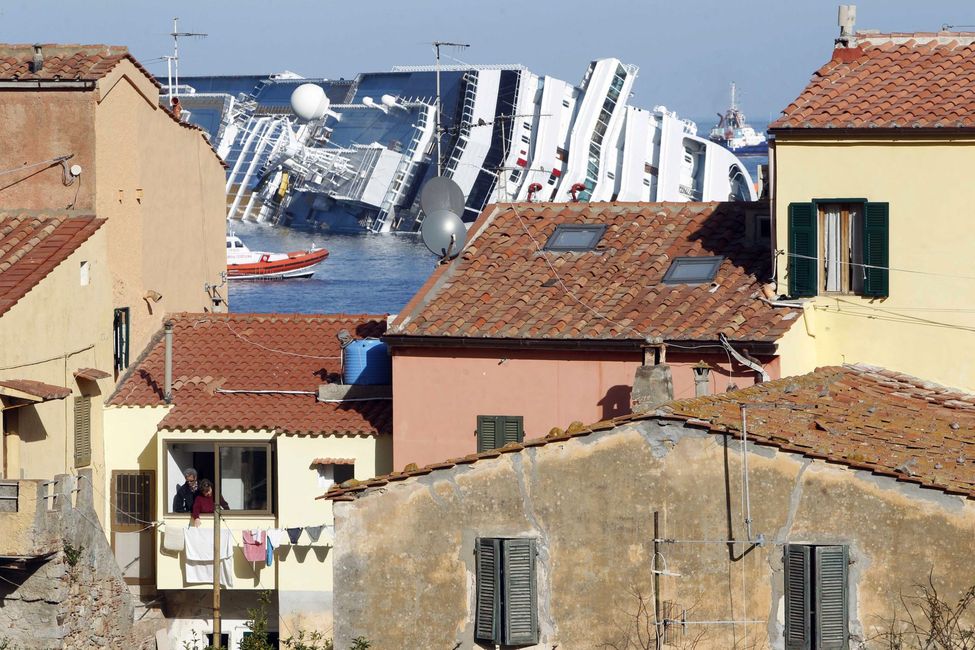 Претърпелият корабокрушение круизен кораб Коста Конкордия, Costa Concordia, се вижда на заден план, край тосканския остров Изола дел Джилио, Италия, събота, 21 януари 2012 г.