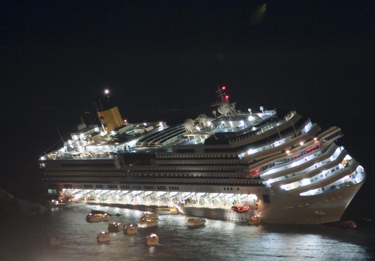 Луксозният круизен кораб Costa Concordia лежи на десния си борд, след като засяда край бреговете на остров Изола дел Джилио, Италия, на 13 януари 2012 г.