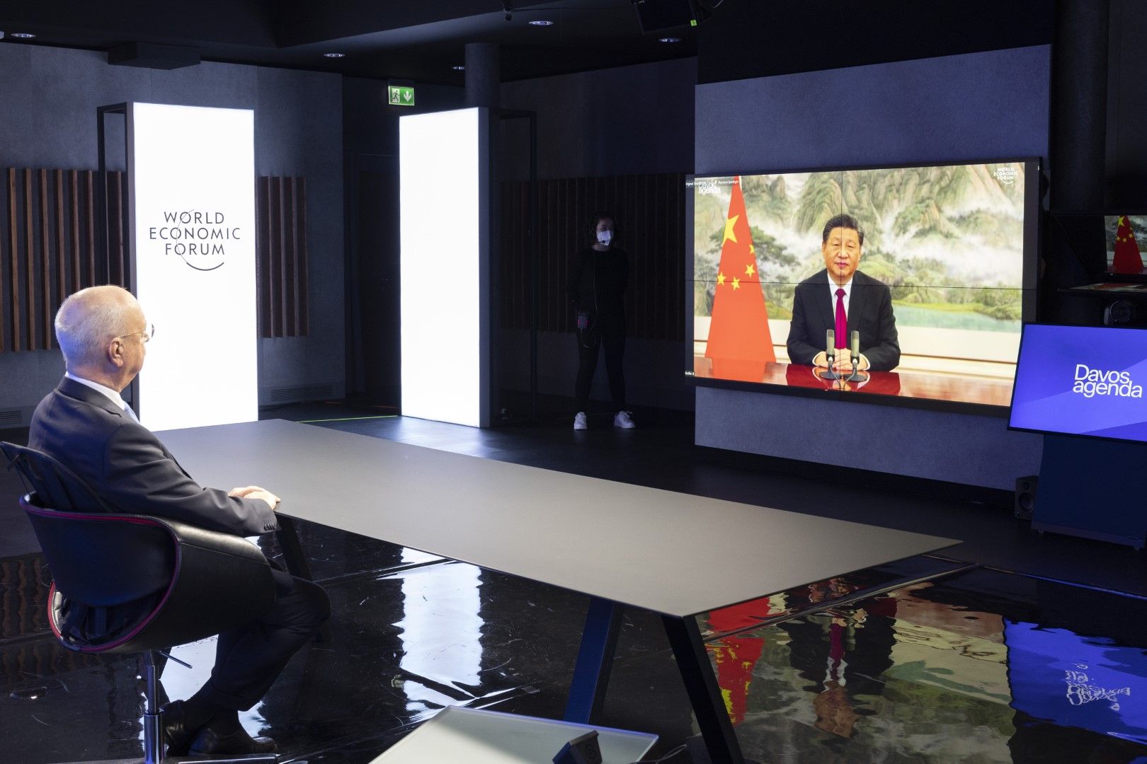 Герман Клаус Шваб, основател и изпълнителен председател на Световния икономически форум, слуша китайския президент Си Дзинпин по време на откриващия се форум "Давос 2022", в Колони, близо до Женева, Швейцария, понеделник, 17 януари, 2022 г.