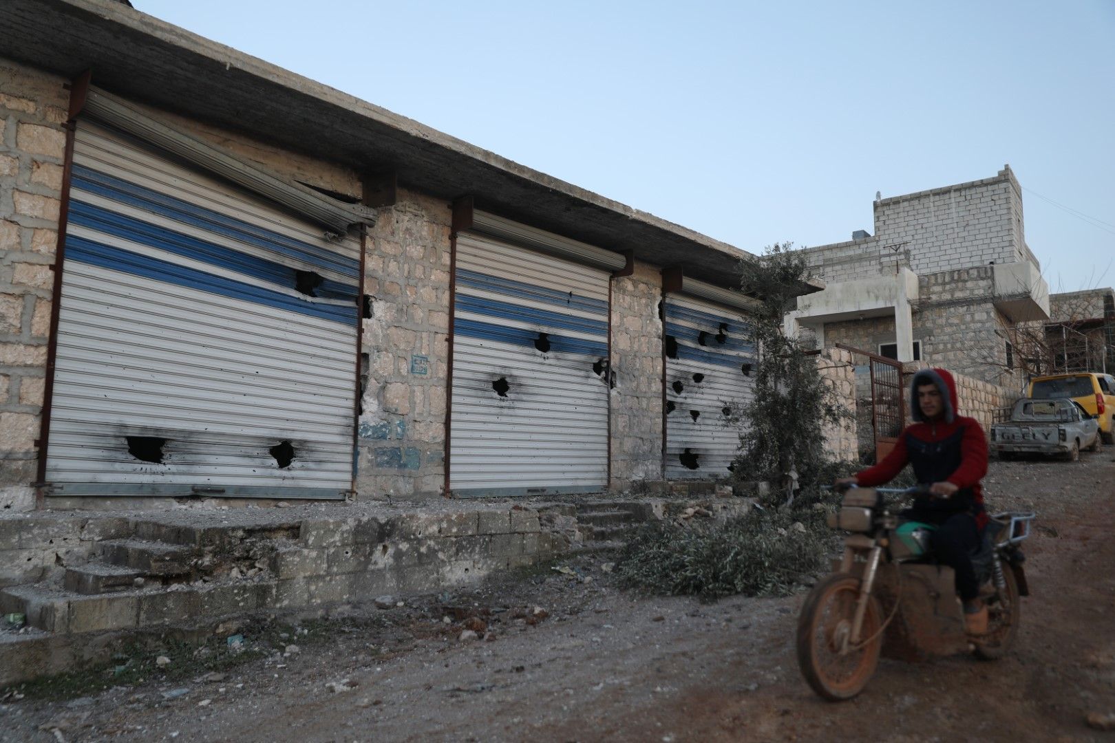 Сириец минава с мотоциклета си покрай надупчени магазини след операция на американските военни в сирийското село Атме в провинция Идлиб