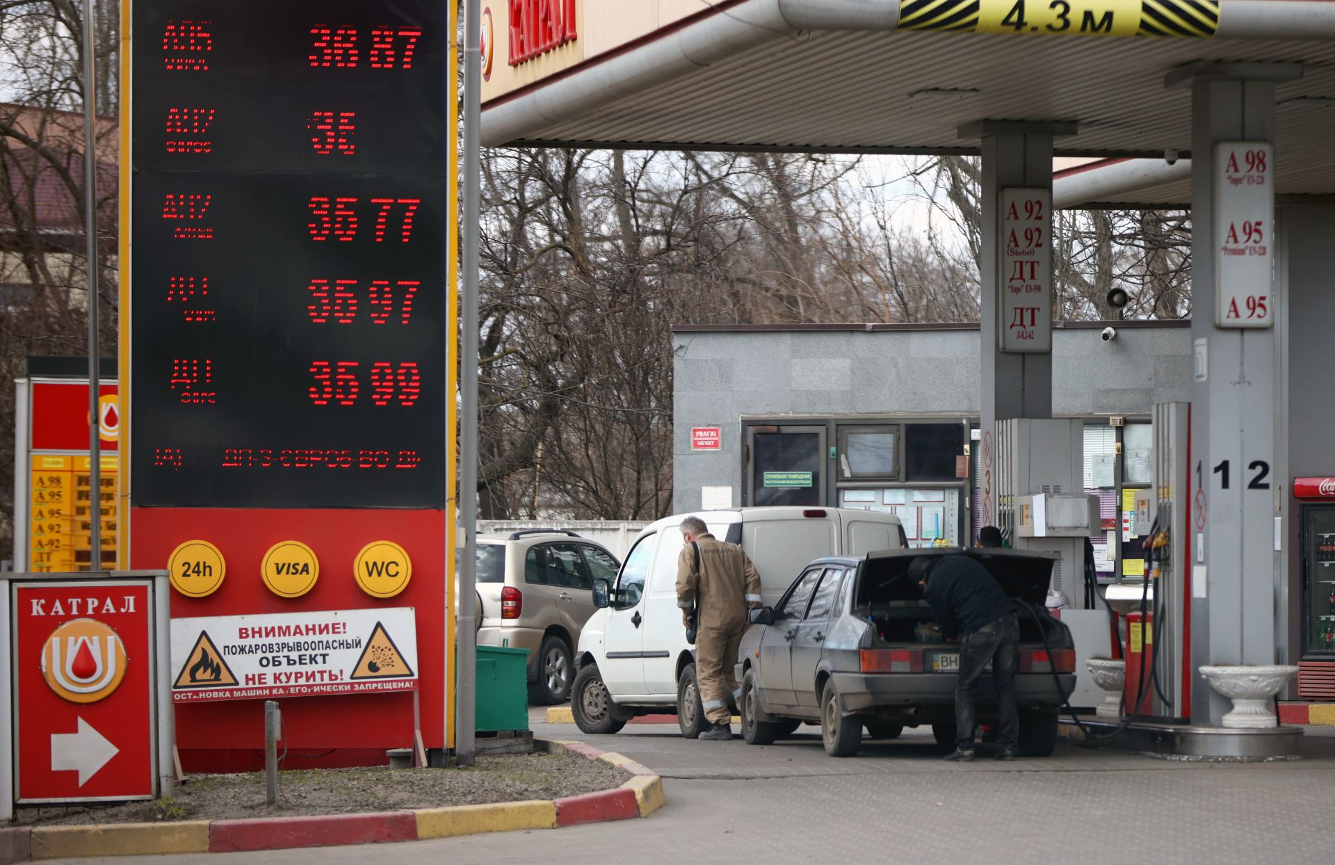 Мъж пълни туби с гориво в багажника на колата си на бензиностанция в Одеса