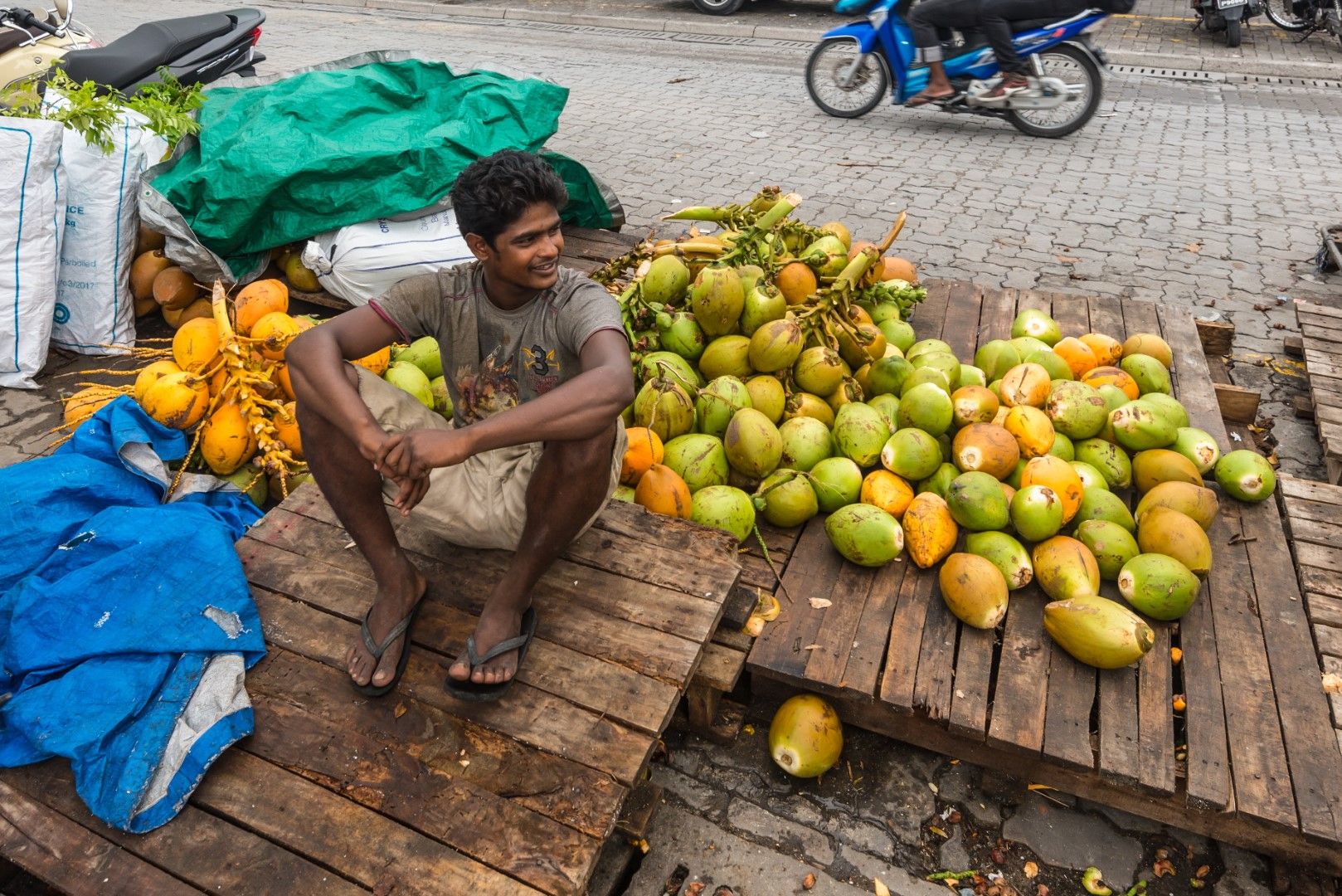 Местен мъж продава кокосови орехи на улицата в Мале
