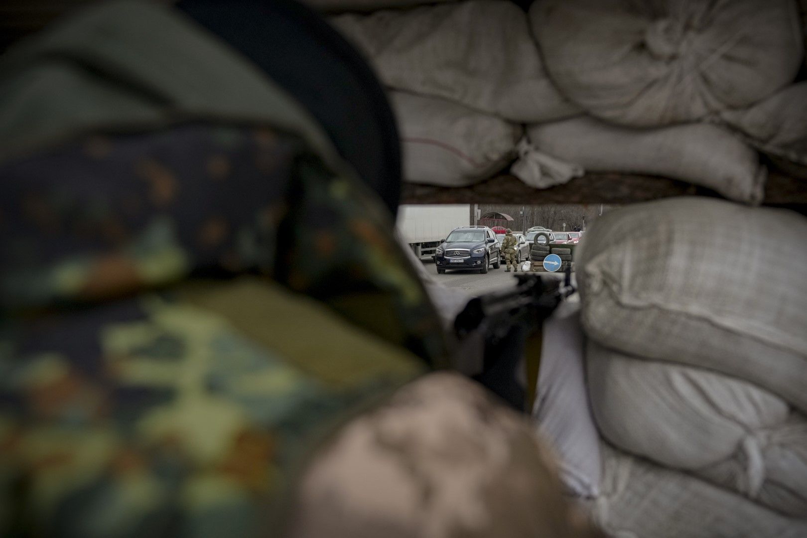 Украински военнослужещ наблюдава контролно-пропускателен пункт зад чували с пясък на главен път в Киев, Украйна, понеделник, 7 март 2022 г.