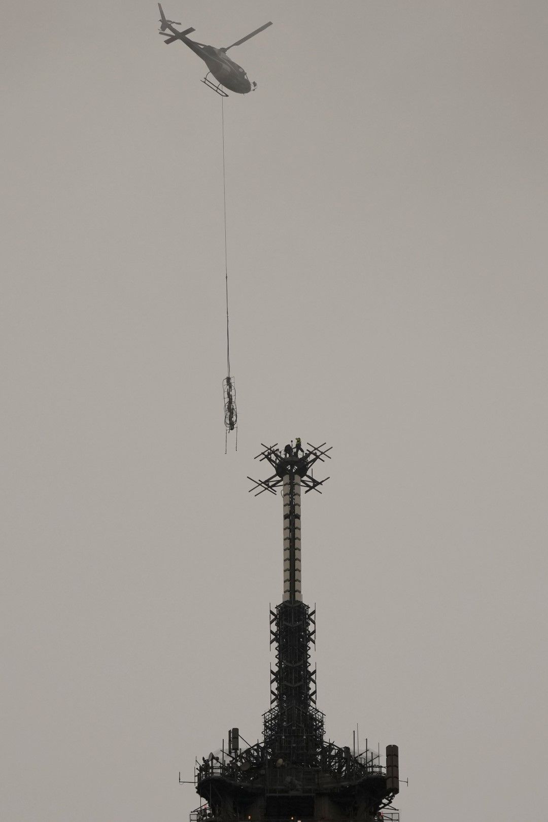 Хеликоптер Eurocopter инсталира новата телекомуникационна антена TDF на върха на Айфеловата кула в Париж във вторник, 15 март 2022 г.