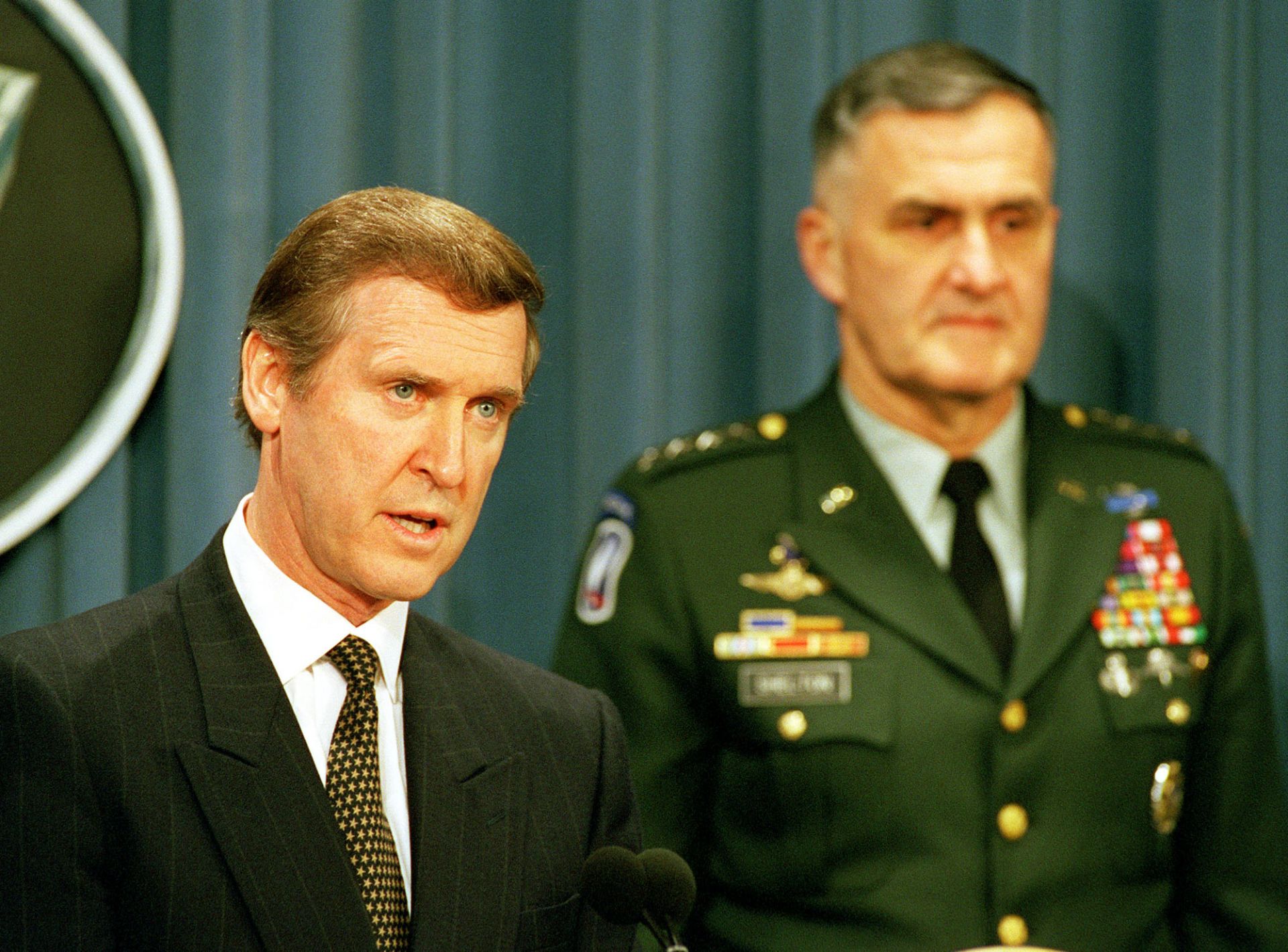 Министърът на отбраната на САЩ Уилям С. Коен (вляво) отговаря на репортерски въпрос по време на брифинг на Пентагона с председателя на Обединения началник на щабовете генерал Хенри Х. Шелтън относно операцията на НАТО Съюзнически сили на 24 март 1999 г.