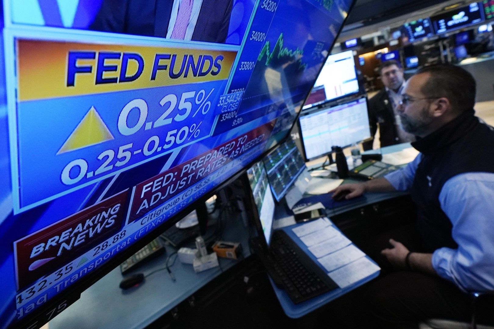 Телевизионен екран на пода на Нюйоркската фондова борса, сряда, 16 март 2022 г., показва решението на Федералния резерв да повиши основния лихвен процент с 0,25%