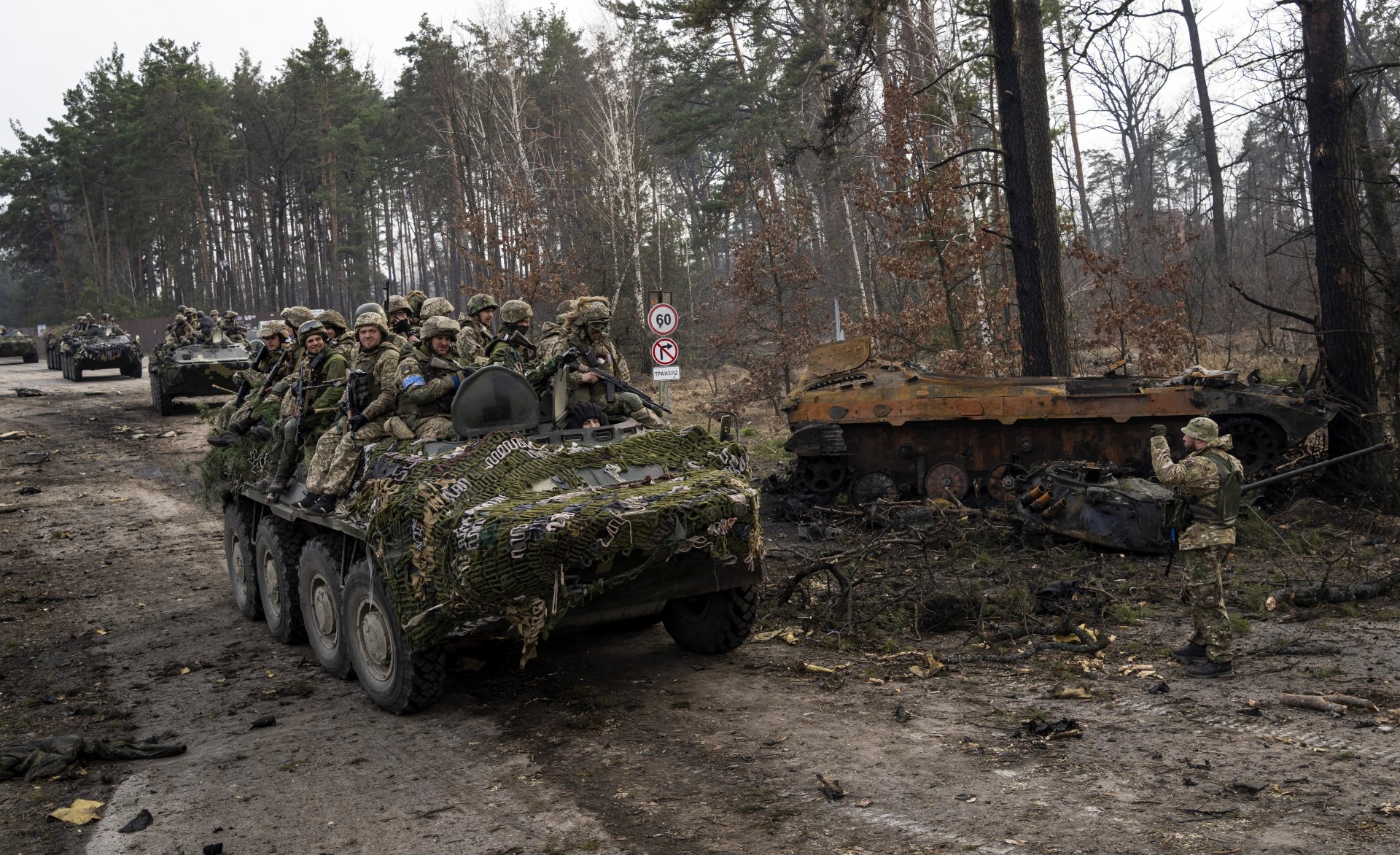 Украински военни преминават покрай поразен руски танк край Киев