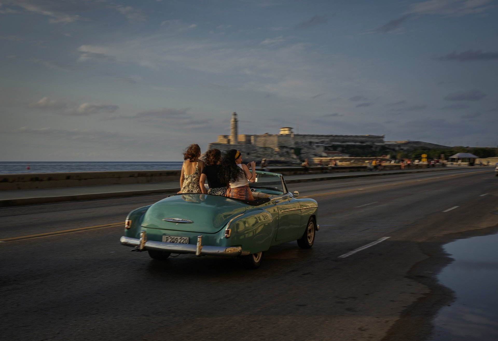Туристи пътуват по широката улица "Малекон" в Хавана с ретро американска кола, понеделник, 16 май 2022 г.