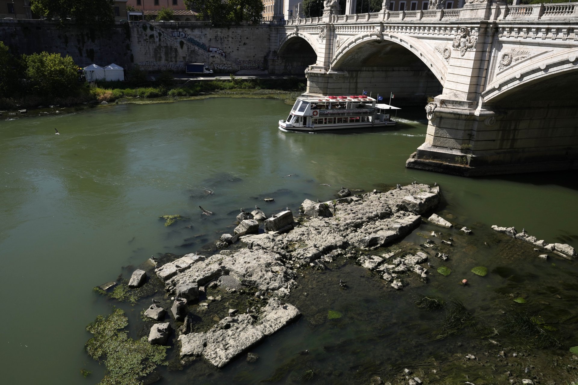 Корабче минава покрай руините на древния римски Неронов мост, обикновено потопени в Тибър, Рим, четвъртък, 30 юни 2022 г.