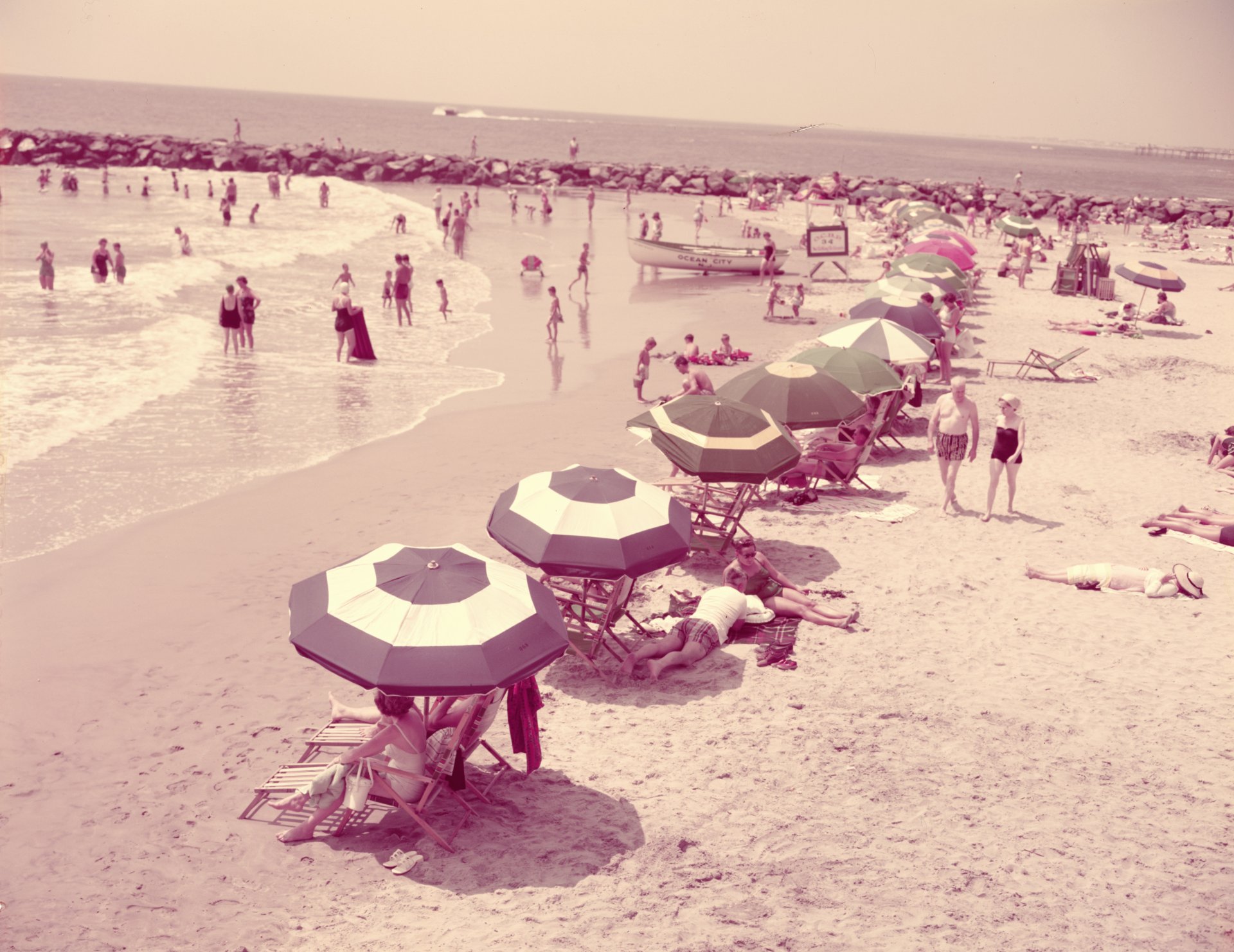 1950-те години: лятна плажна сцена, хора, релаксиращи на пясъчен бряг, Ню Джърси. 
