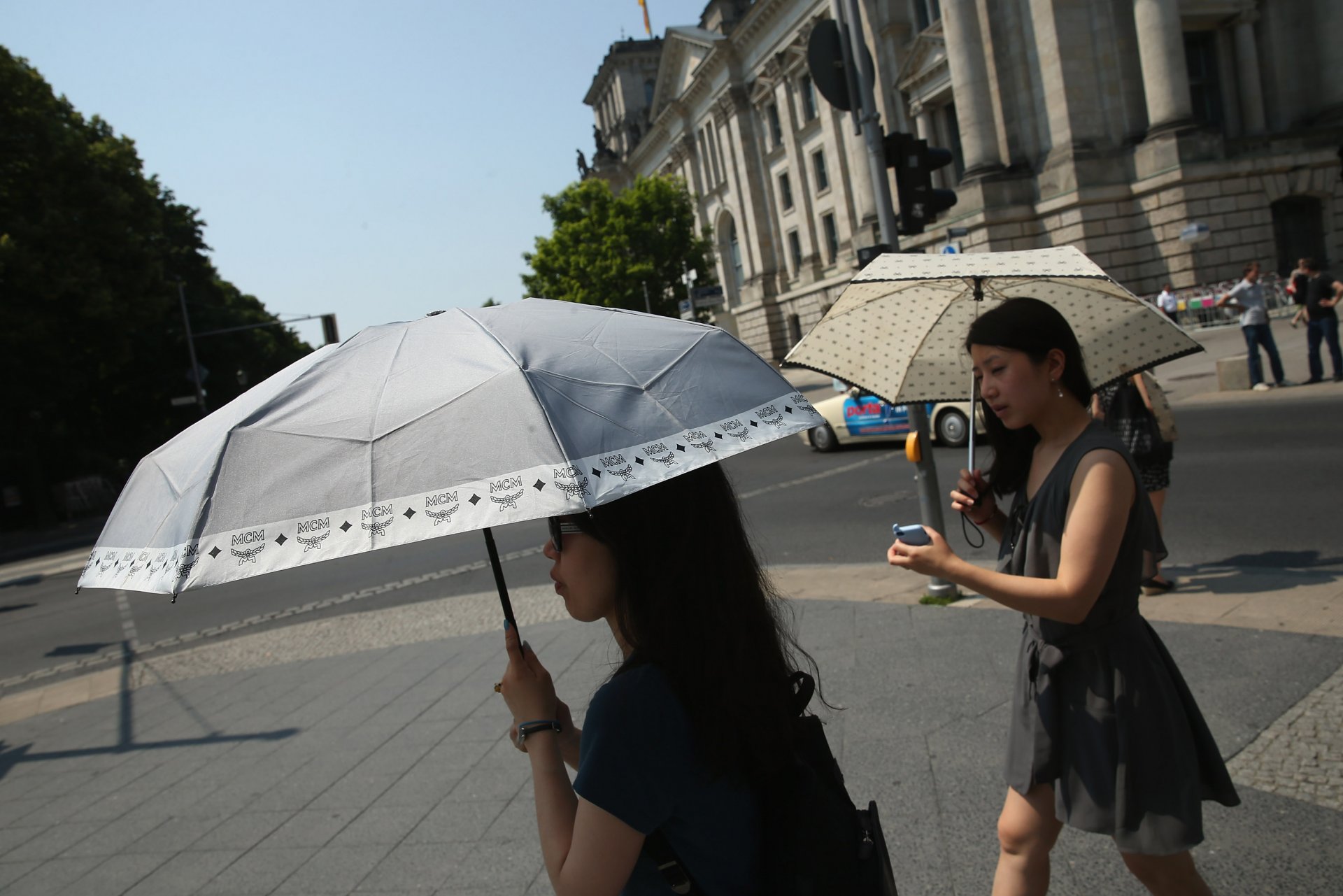  Две млади жени носят чадъри в горещ летен ден в центъра на града на 20 юни 2013 г. в Берлин, Германия. Централна Европа е в плен на гореща вълна, при която температурите в някои региони достигнаха до 38 градуса по Целзий. 