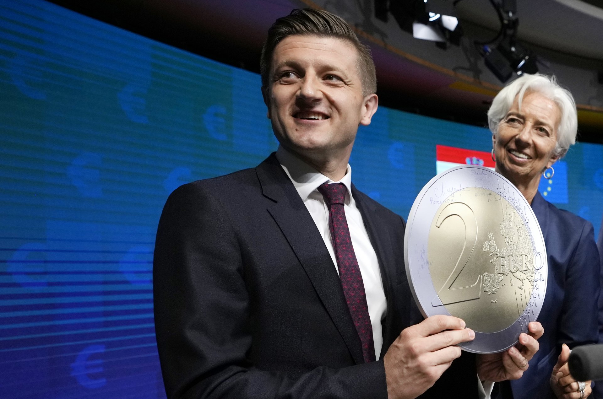 Министърът на финансите на Хърватия Здравко Марич, вляво, държи картонена евро монета, докато позира с президента на Европейската централна банка Кристин Лагард след церемонията за присъединяване на Хърватия към еврозоната, 12 юли 2022 г.