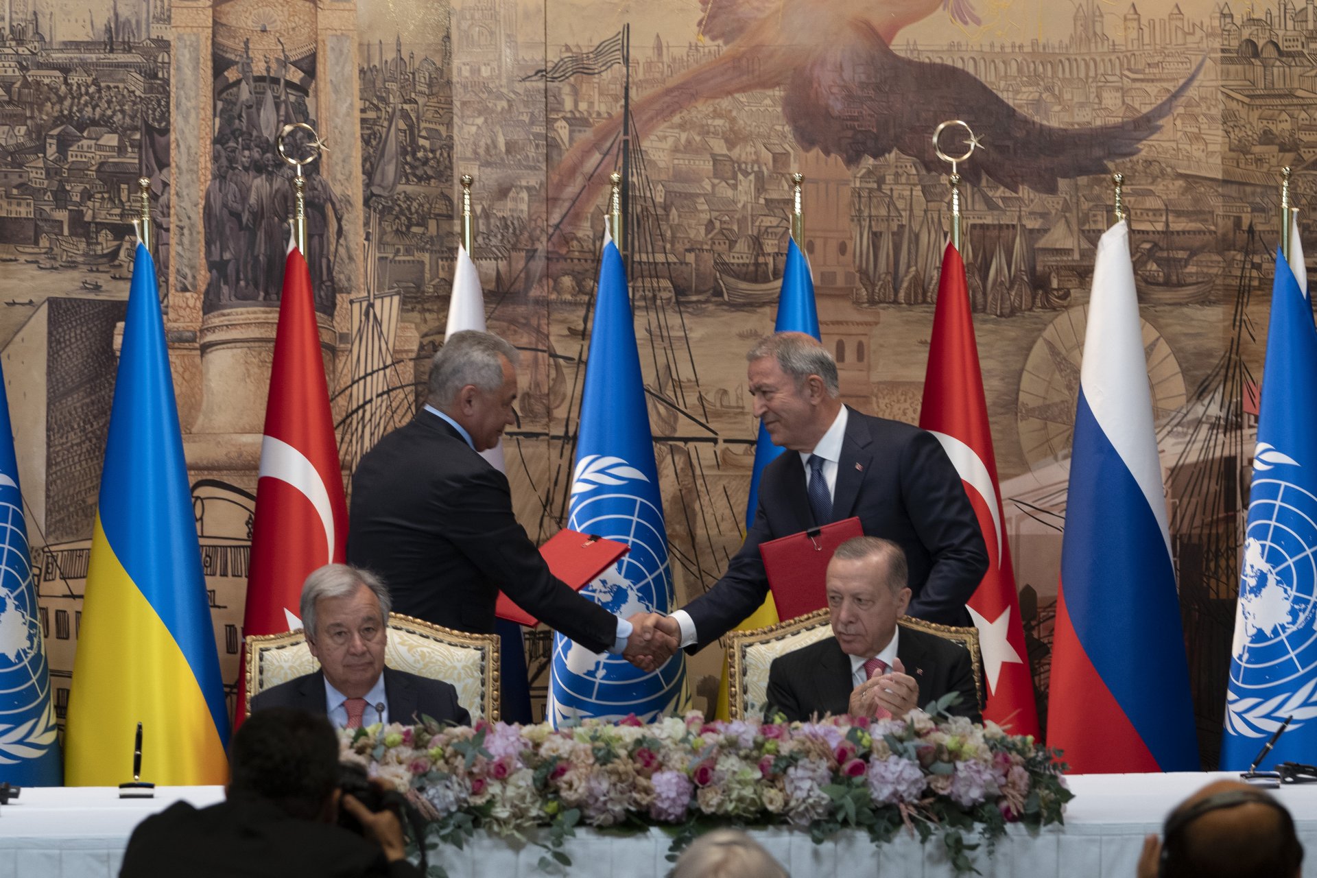 Турският президент Реджеп Тайип Ердоган, вдясно, и генералният секретар на ООН Антонио Гутериш на преден план, докато военните министри на Русия и Турция Сергей Шойгу и Хулуси Акар се поздравяват след подписването на сделката за зърното