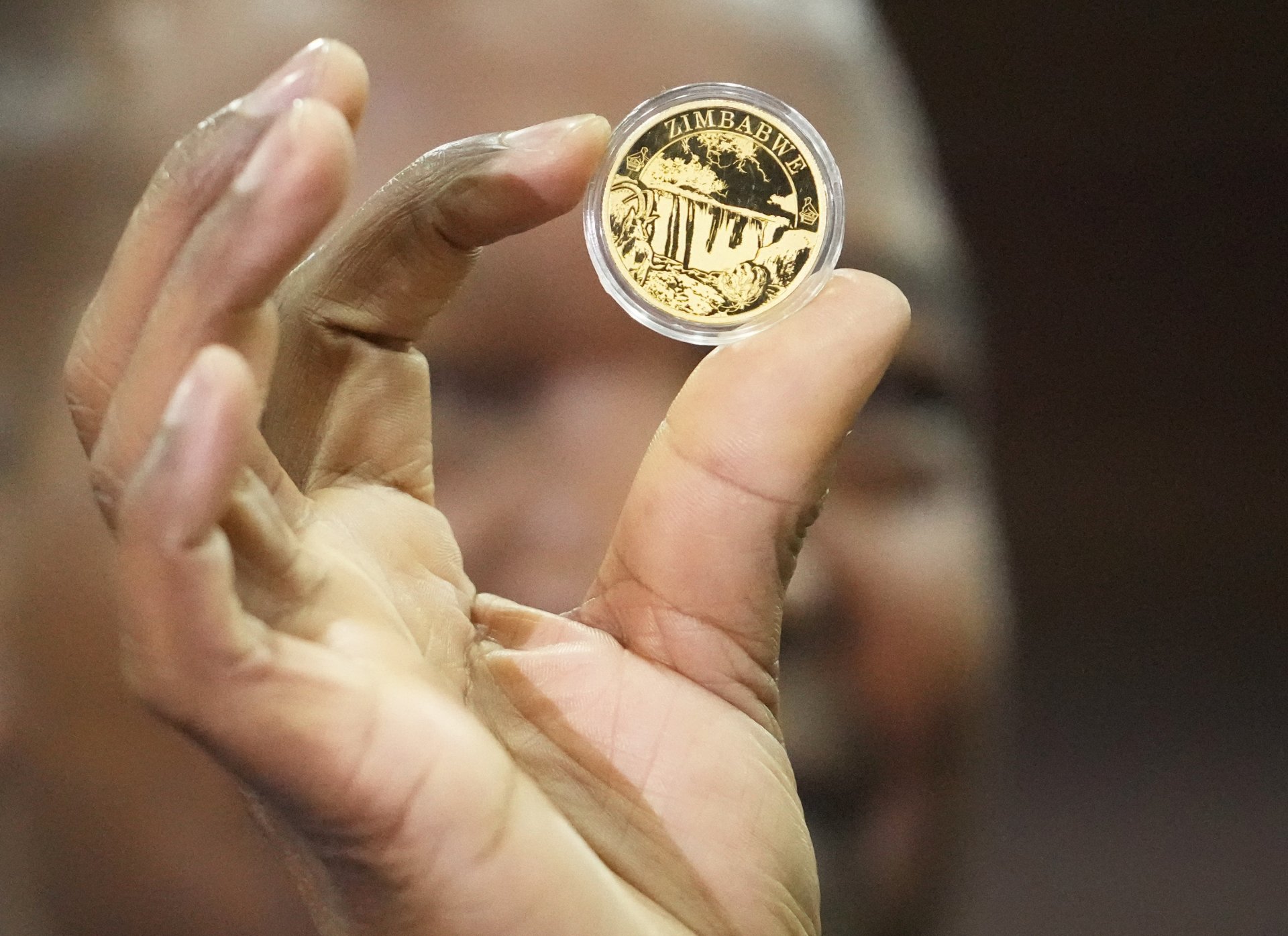 Гъверньорът на Централната банка на Зимбабе Джон Мангудя държи мостра от златна монета при пускането й в Хараре, понеделник, 25 юли 2022 г.