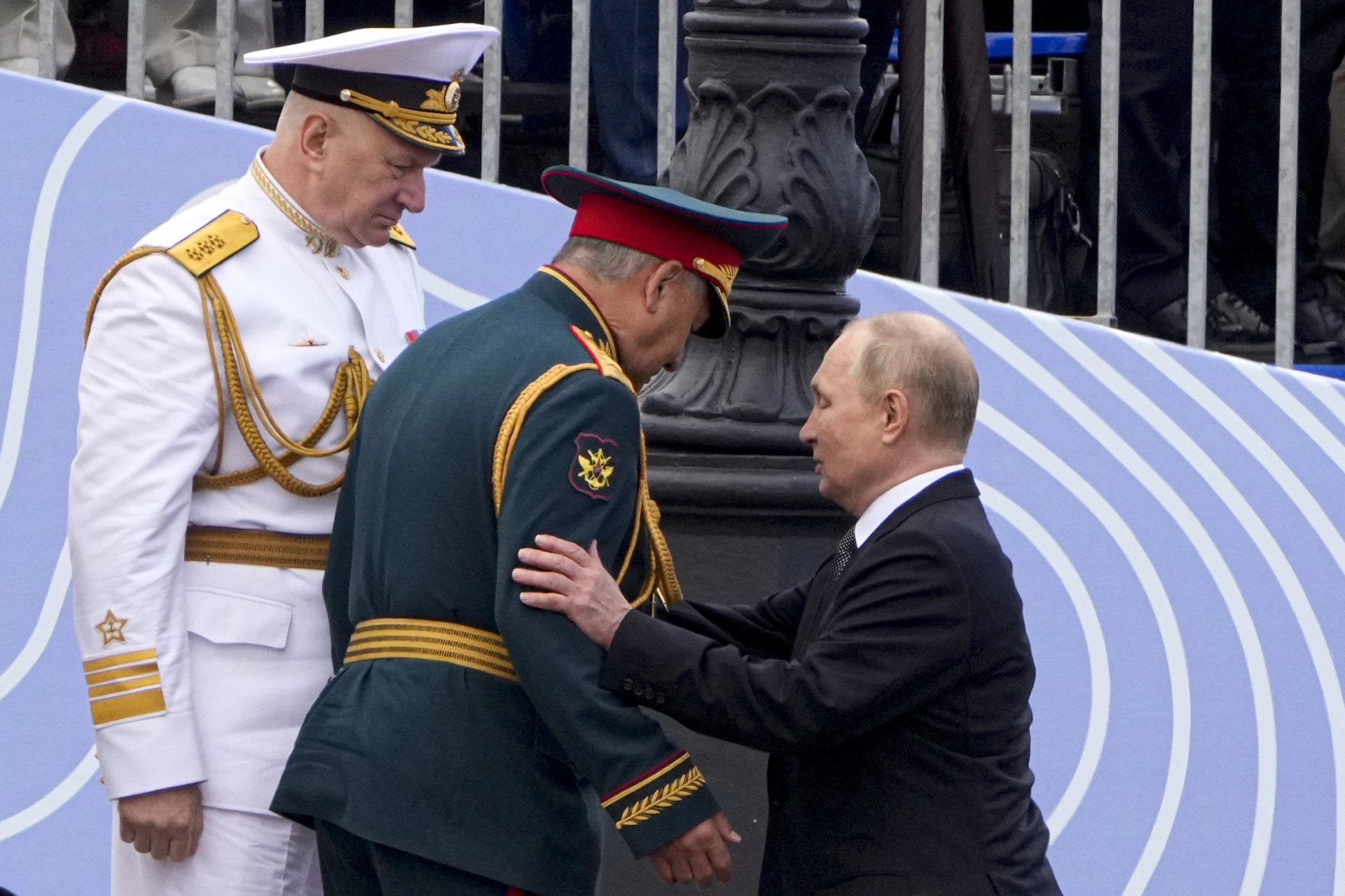 Владимир Путин помага на военния министър Сергей Шойгу да слезе по стълбата