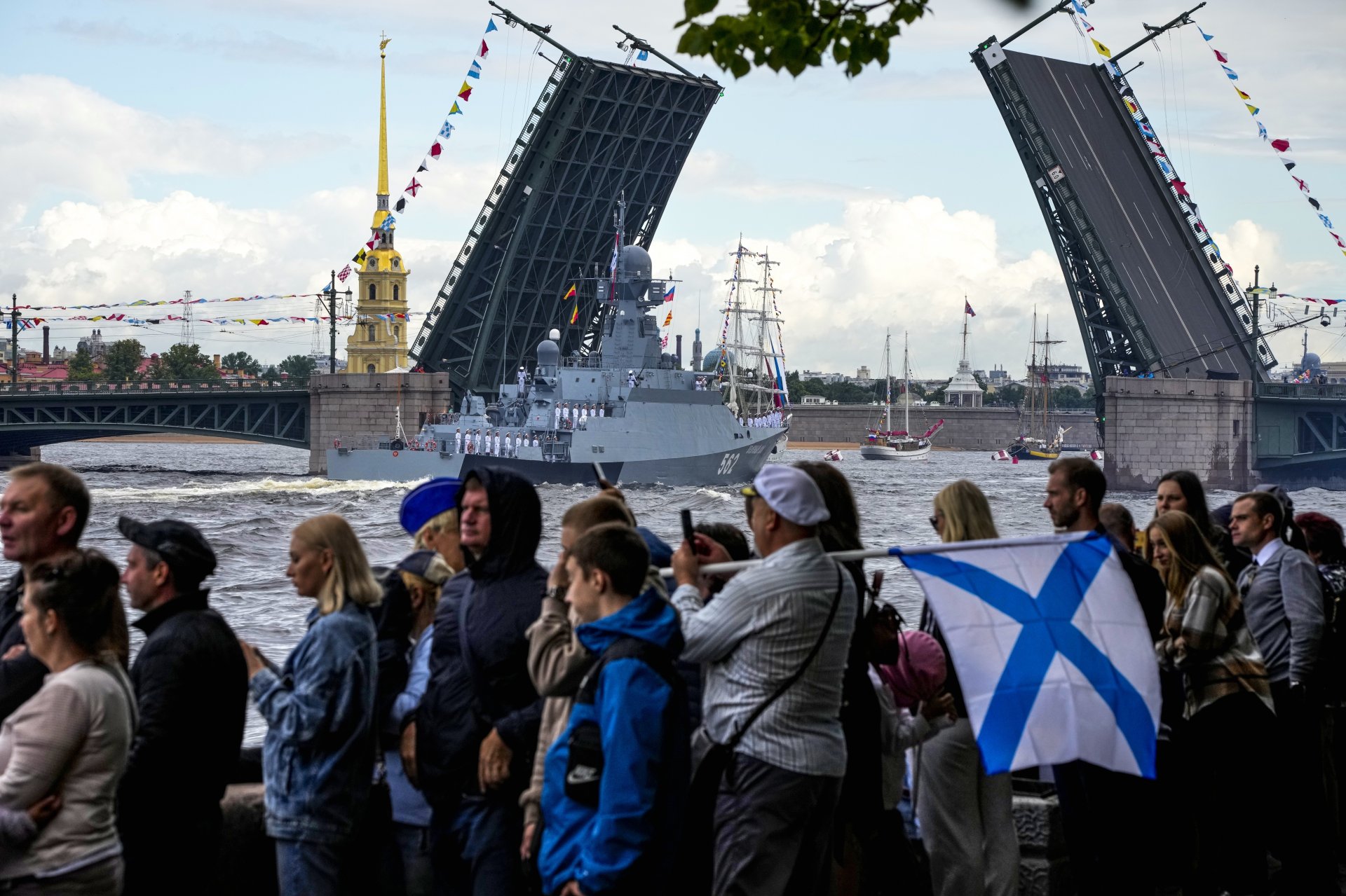Зрителите гледат как "Зелени Дол", ракетен военен кораб, се носи покрай подвижни мостове, издигащи се над река Нева по време на честването на Деня на ВМС в Санкт Петербург