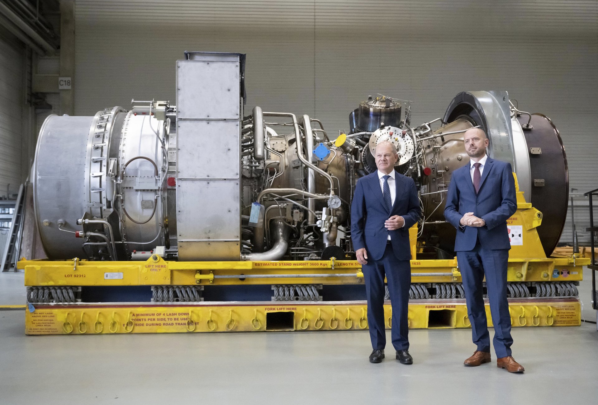 Германският канцлер Олаф Шолц, вляво, стои до Кристиан Брух, главен изпълнителен директор на Siemens Energy, застанали пред турбината, ремонтирана в Канада за газопровода "Северен поток-1"
