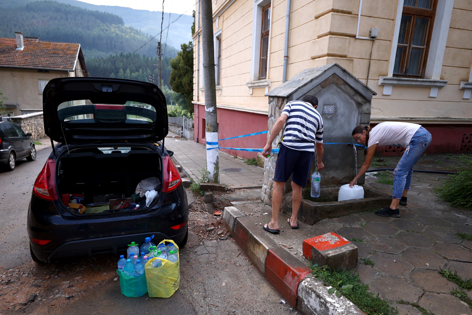 Местните хора си наливат изворна вода от чешма в село Искрец, 17 август