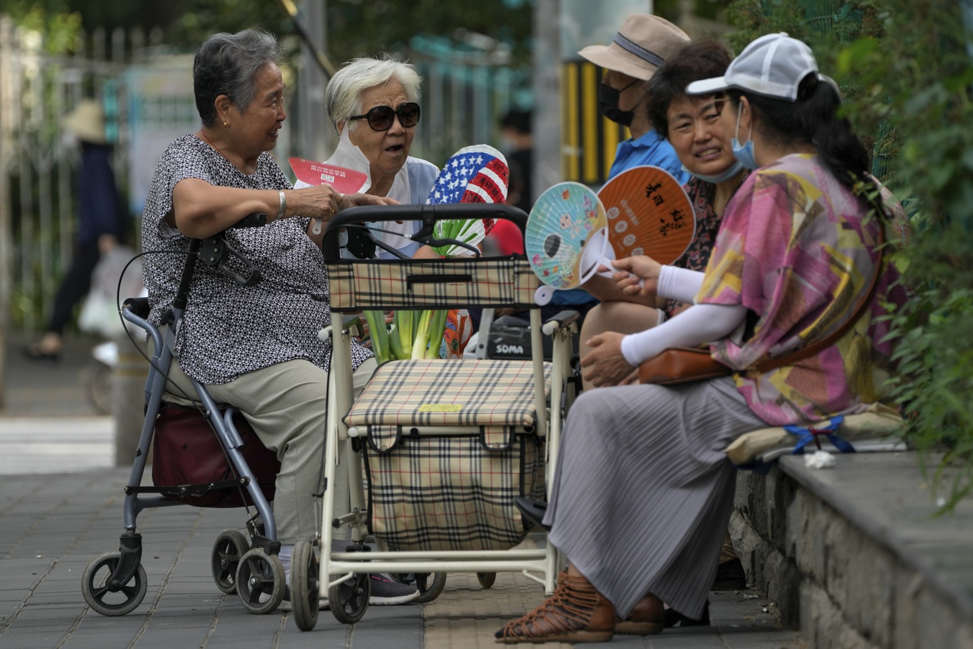Жители на Пекин си веят с ветрила, докато разговарят, неделя, 21 август 2022 г.