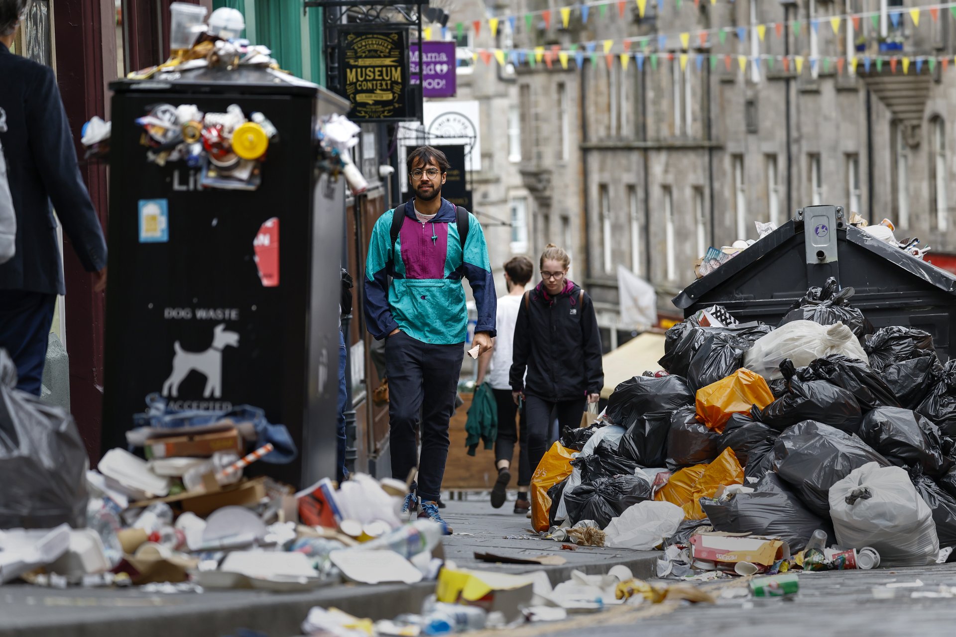 Граждани минават покрай големи купчини боклук в Единбург, Шотландия. Събирането на контейнери за отпадъци е преустановено в шотландската столица за 10 дни, тъй като служителите в сектора са в стачка. 