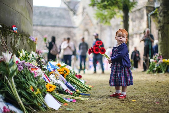 Moмиченце поднася цветя в памет на покойната кралица Елизабет II пред двореца Холирудхаус 