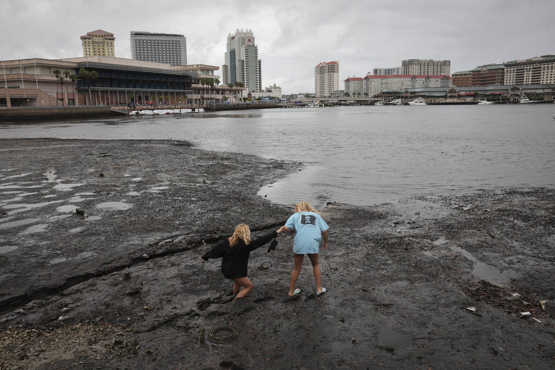 Сестрите Ейнджъл Дисброу (дясно) и Селена Дисброу се разхождат по брега - водата се е оттеглила от залива с приближаването на урагана Иън 