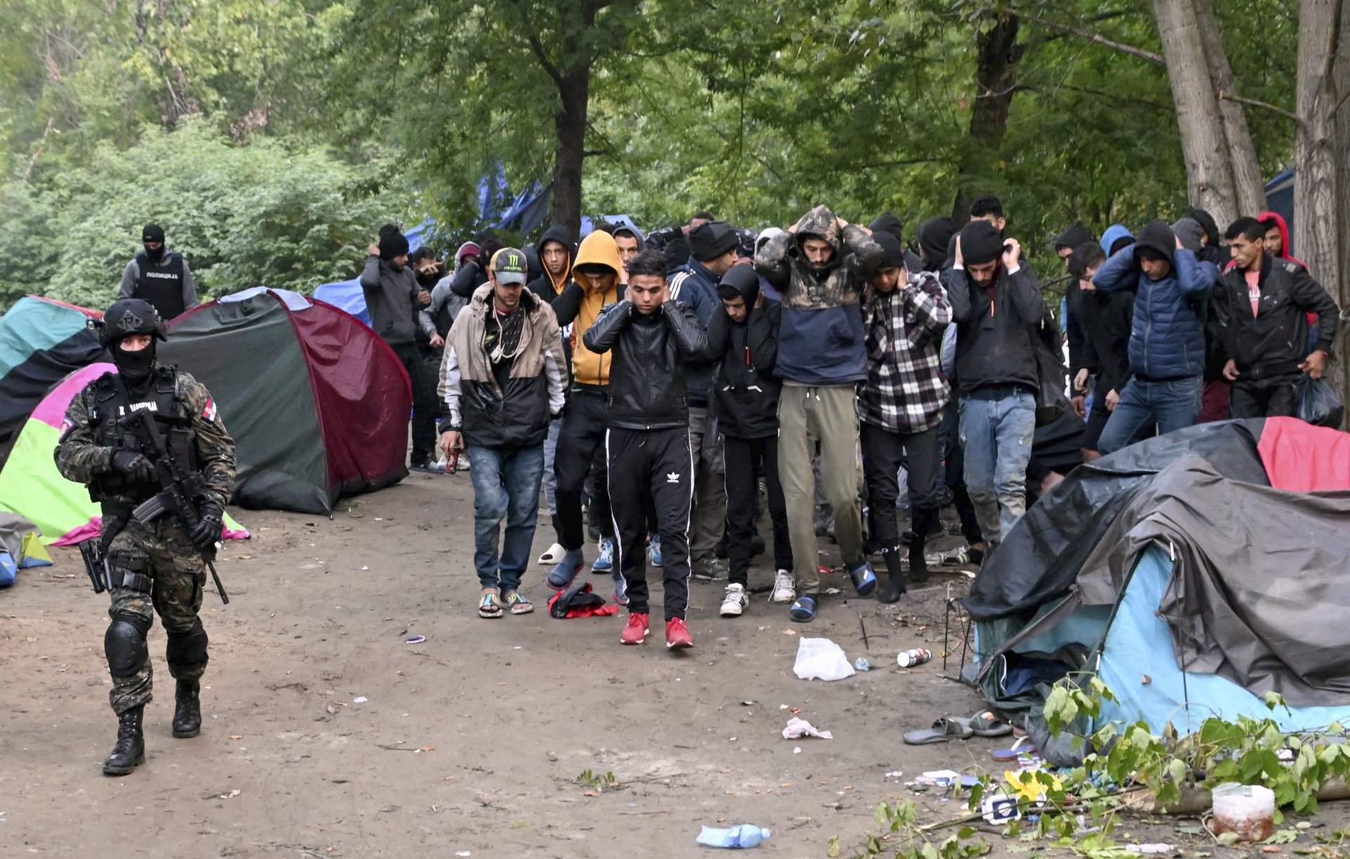 Сръбски полицаи ескортират мигранти близо до село Сръбски Кустур на 5 октомври 2022 г. Полицията нахлу в импровизиран лагер близо до границата с Унгария, където откри 200 мигранти