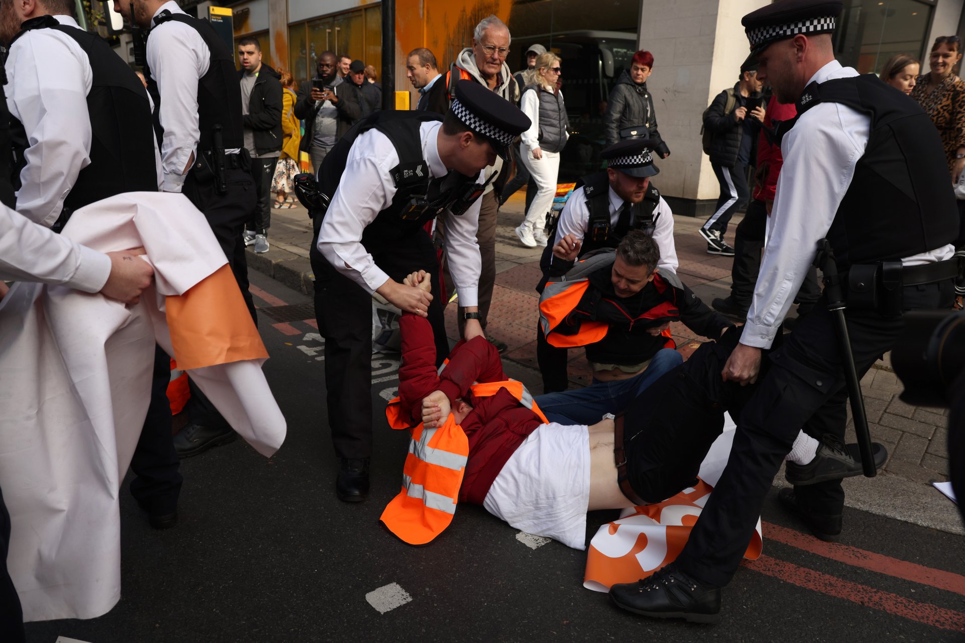  Полицейски служители отстраняват демонстранти, блокиращи движението по Парк Лейн в Мейфеър на 16 октомври 2022 г. в Лондон, Англия