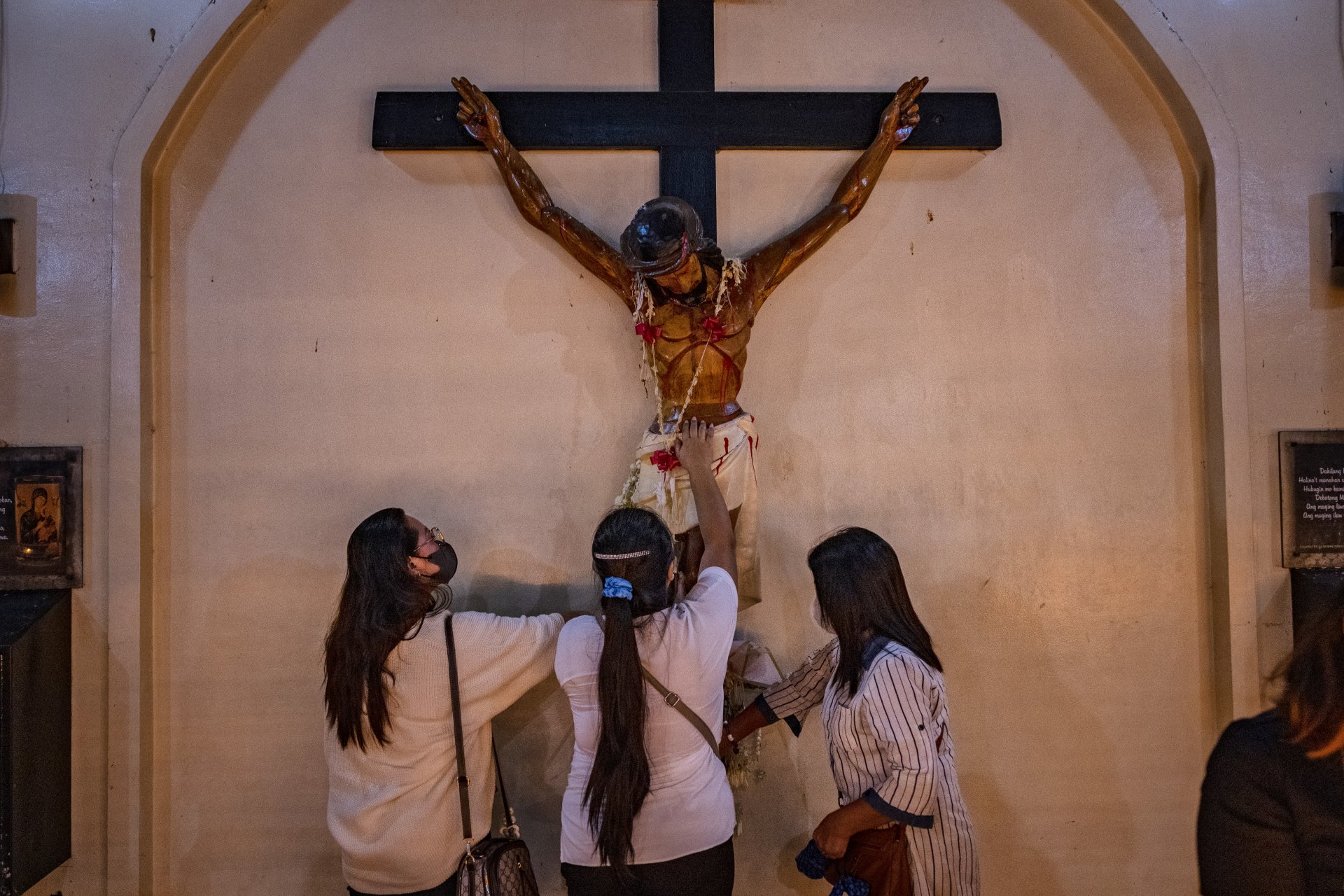 : Филипински католици докосват разпятие, след литургия преди зазоряване, в църквата Бакларан на 20 декември 2022 г. 