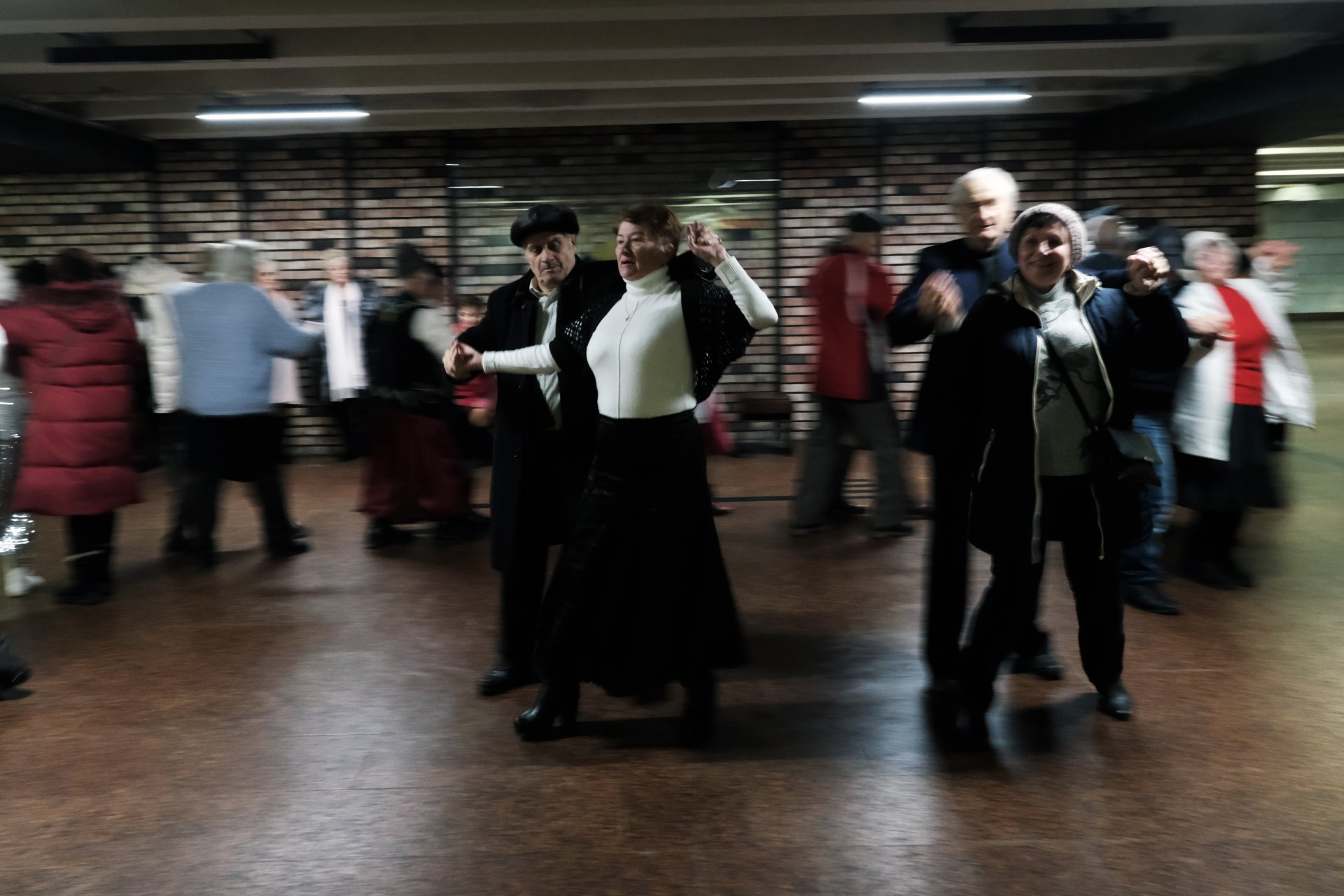 Възрастни двойки участват в традиционно танцово събиране в подземието на мол на 01 януари 2023 г. в Киев, Украйна. 
