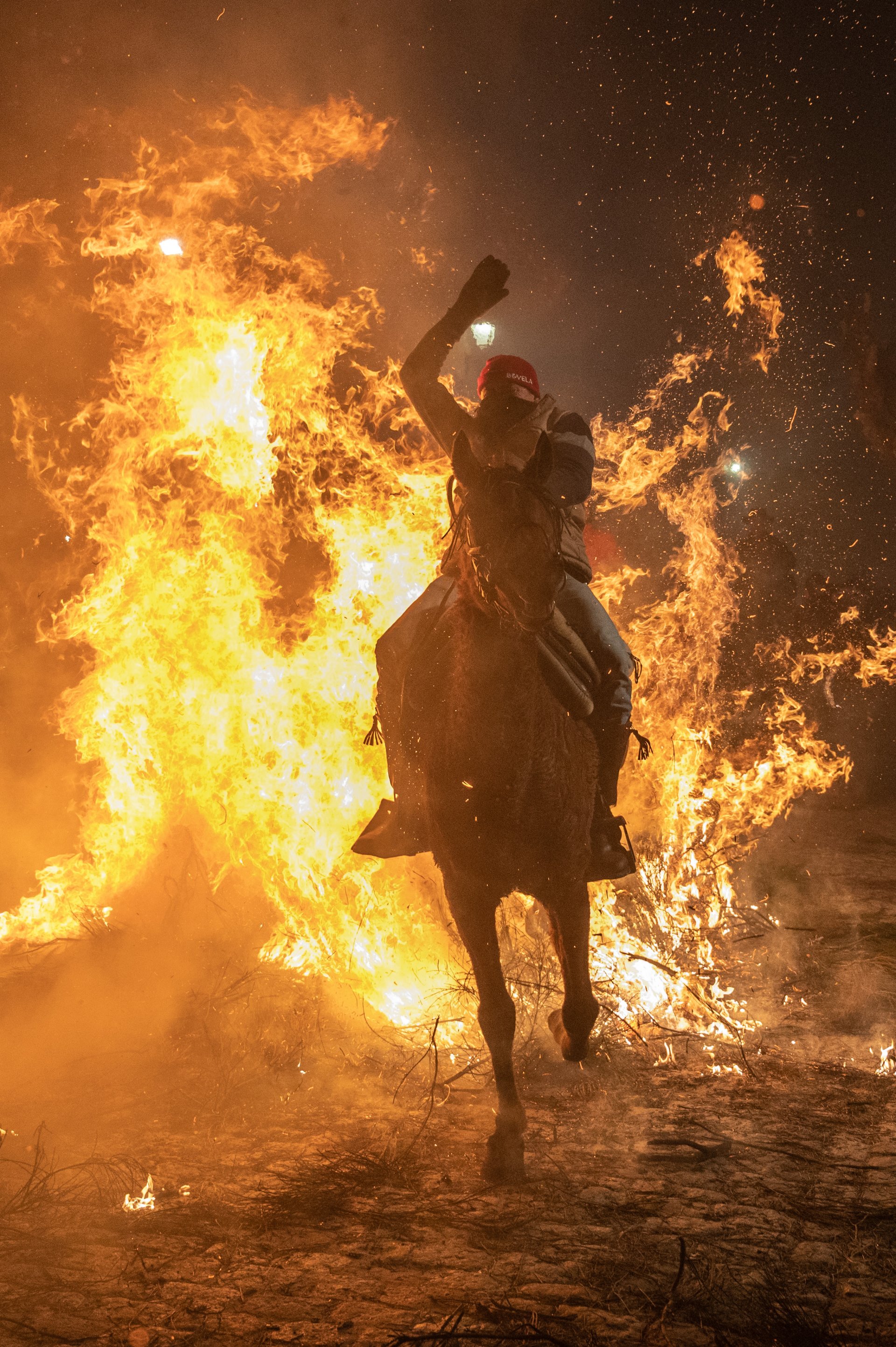 САН БАРТОЛОМЕ ДЕ ПИНАРЕС, ИСПАНИЯ – 16 ЯНУАРИ: Конен ездач прескача огън на 16 януари 2023 г. в Сан Бартоломе де Пинарес, Испания. Конни ездачи прескачат огньове по време на традиционния ритуал в чест на Сан Антонио Абад (Свети Антоний Абат), покровител на домашните животни, известен като Las Luminarias, който има за цел да пречисти животните с дима на огньовете и да ги защити за идната година. (Снимка от Маркос дел Мазо/Гети изображения)